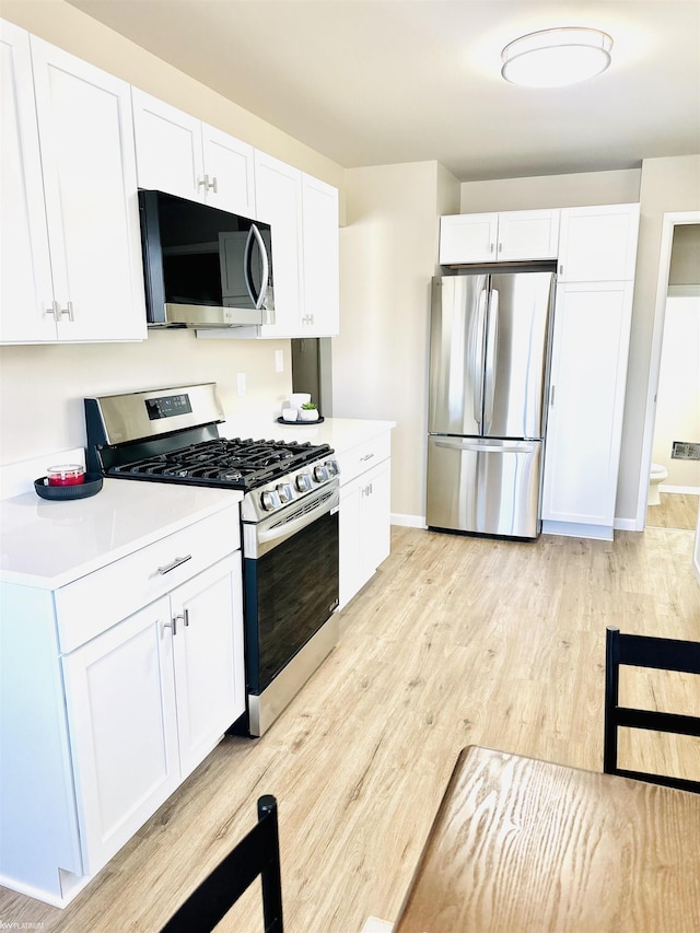 kitchen featuring stainless steel appliances, light hardwood / wood-style floors, and white cabinets