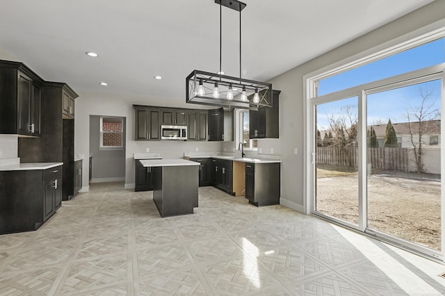 kitchen with dark brown cabinetry, hanging light fixtures, sink, and a center island