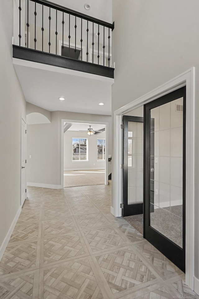 corridor featuring a towering ceiling and light parquet flooring