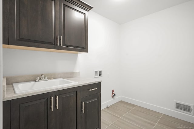 washroom with cabinets, light tile patterned flooring, sink, and washer hookup