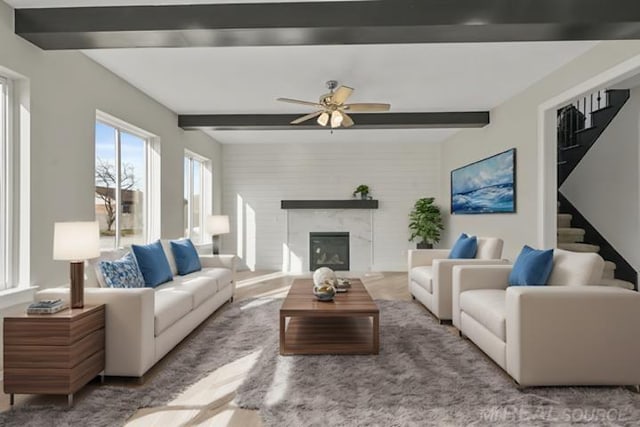 living room featuring ceiling fan, a fireplace, and beam ceiling