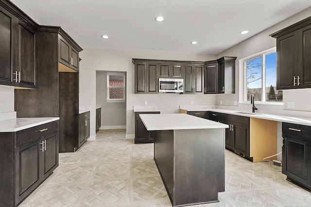 kitchen with light parquet flooring, dark brown cabinets, a center island, and sink