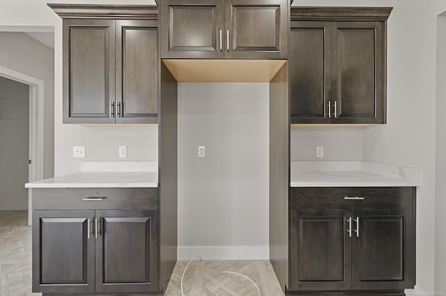 kitchen featuring light stone counters and dark brown cabinets