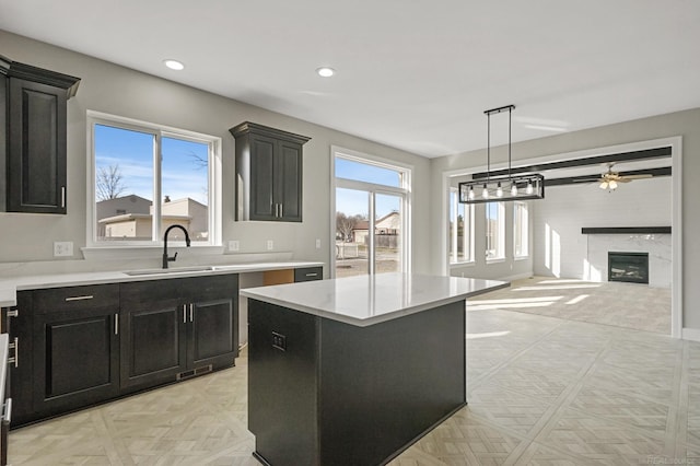 kitchen featuring a healthy amount of sunlight, a center island, sink, and a high end fireplace