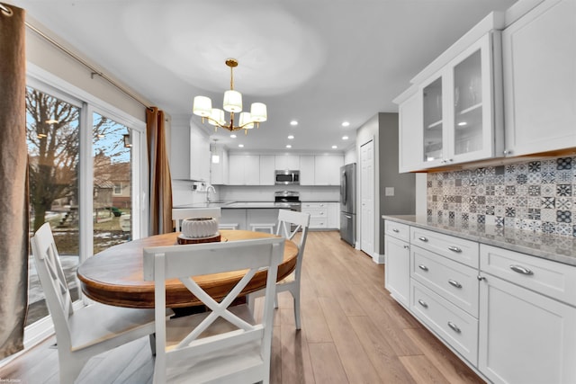 dining room with a notable chandelier, sink, and light wood-type flooring