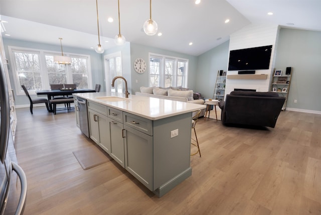 kitchen with sink, gray cabinets, pendant lighting, stainless steel appliances, and a kitchen island with sink