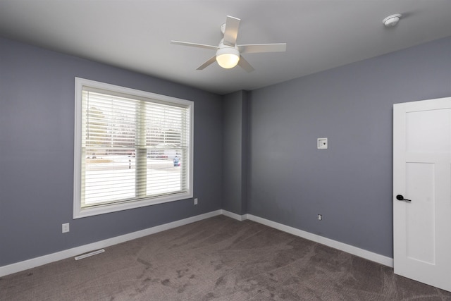 spare room featuring ceiling fan and dark carpet