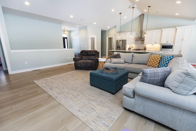 living room featuring high vaulted ceiling and light hardwood / wood-style floors