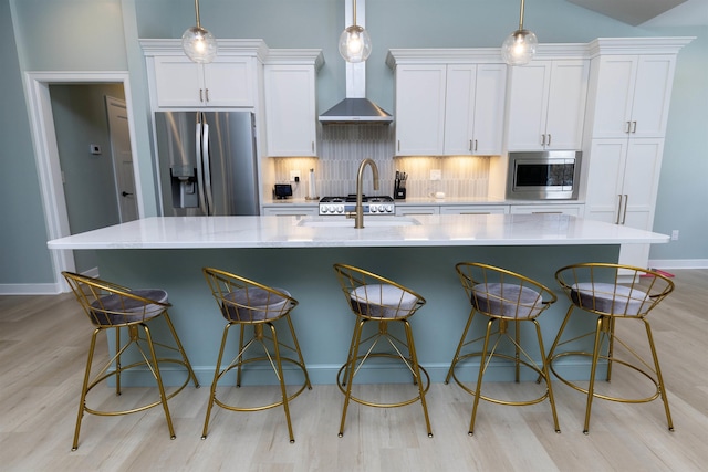 kitchen featuring a large island, wall chimney range hood, and appliances with stainless steel finishes