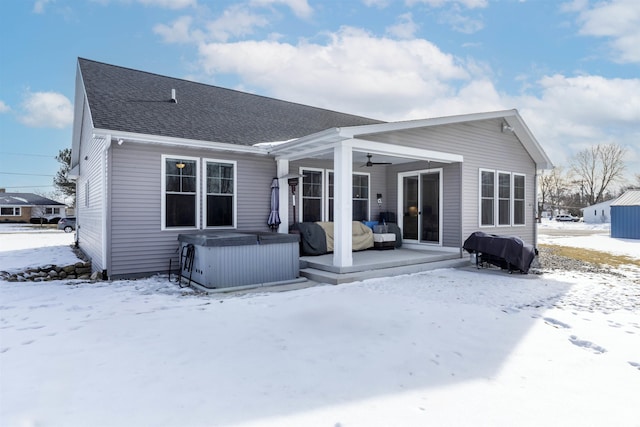 snow covered house with ceiling fan and a hot tub