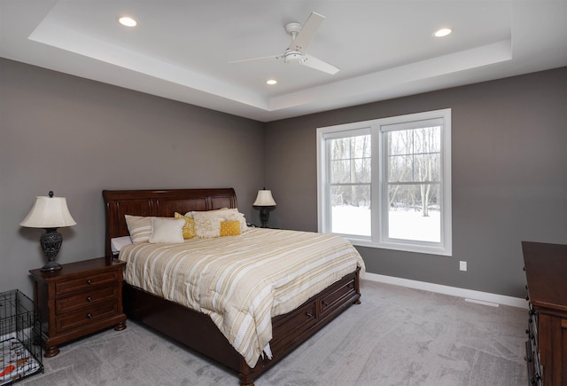 carpeted bedroom with a tray ceiling and ceiling fan