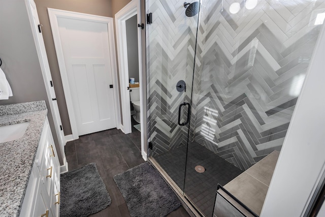 bathroom with vanity, an enclosed shower, and toilet