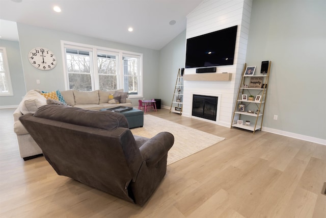 living room with lofted ceiling, a fireplace, and light hardwood / wood-style floors