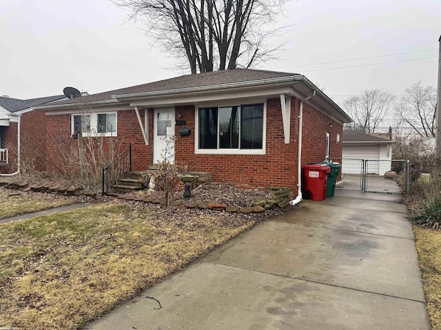 bungalow featuring a detached garage, a gate, fence, and brick siding