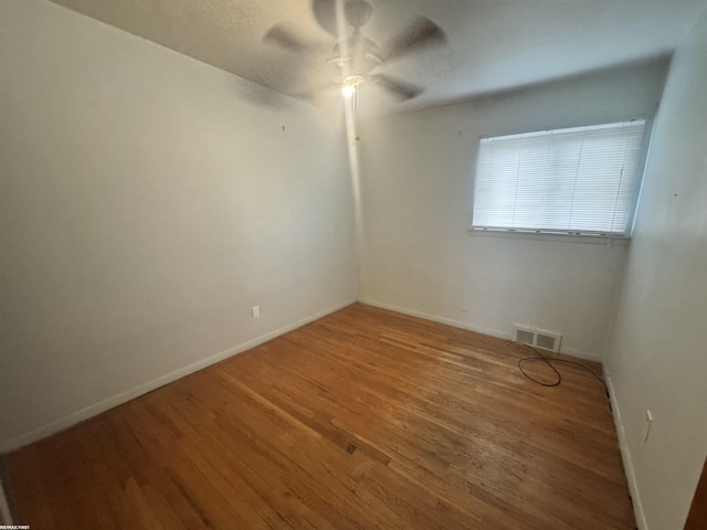 empty room with baseboards, wood finished floors, visible vents, and ceiling fan