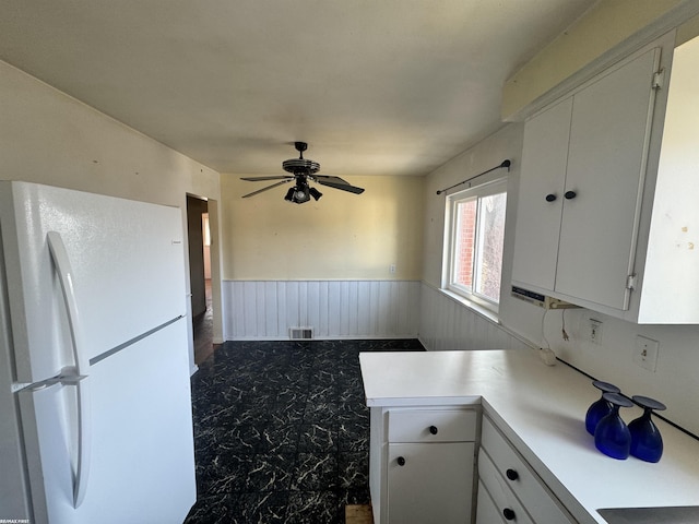 kitchen with visible vents, freestanding refrigerator, light countertops, white cabinets, and wainscoting