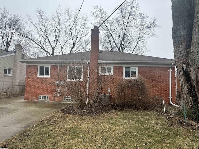 back of house with brick siding and a chimney