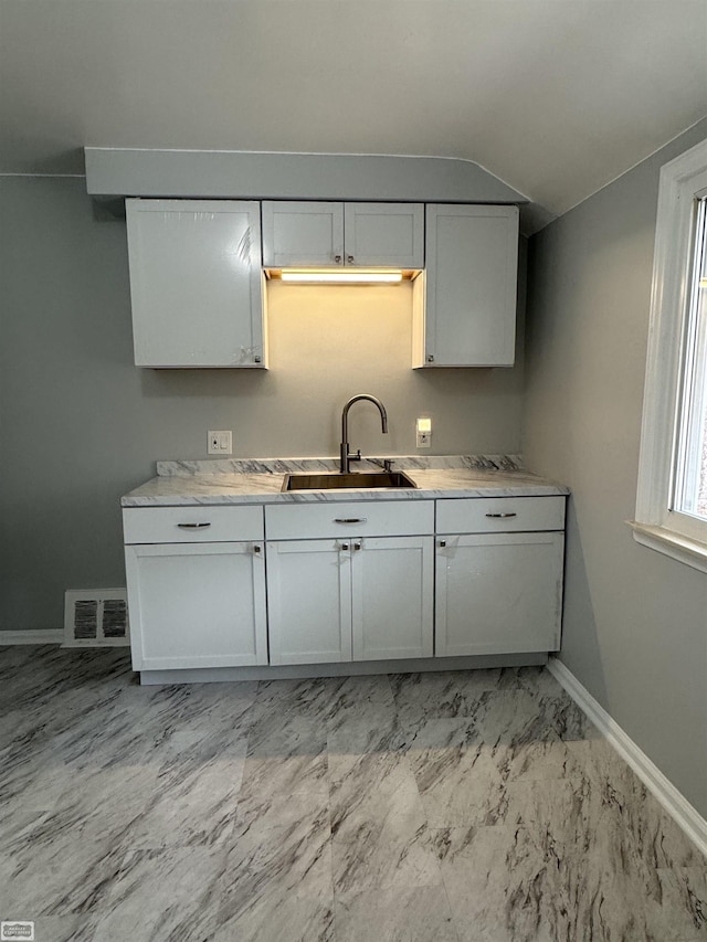 kitchen with sink, vaulted ceiling, and white cabinets