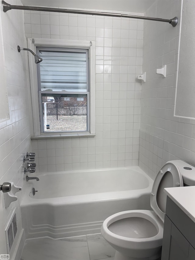 full bathroom with vanity, toilet, tile walls, and tiled shower / bath