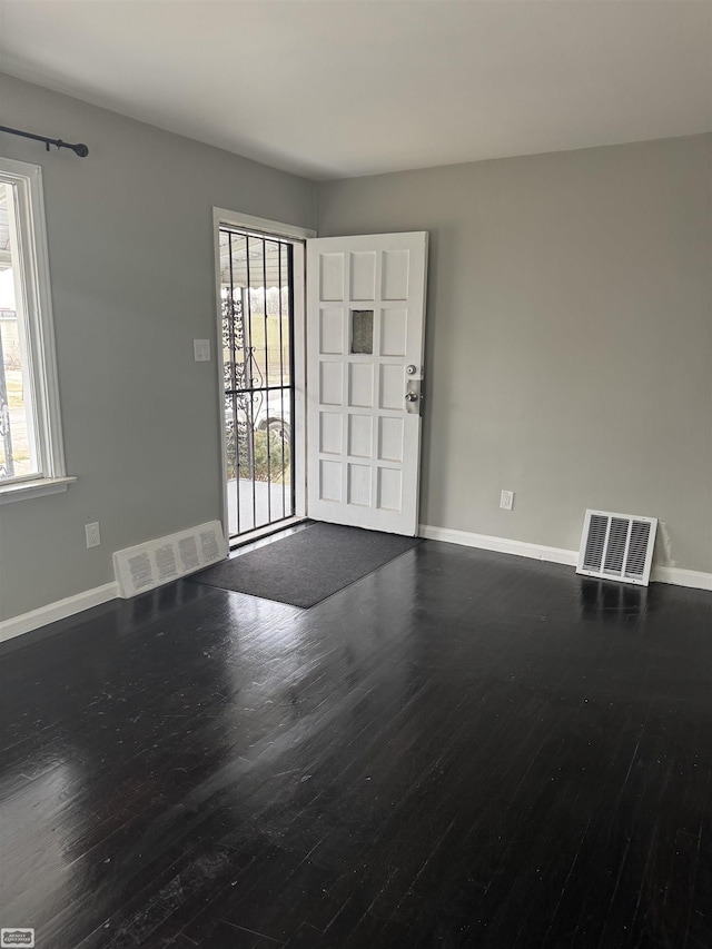 unfurnished room featuring a healthy amount of sunlight and dark hardwood / wood-style floors