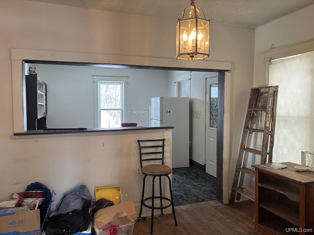 kitchen with hanging light fixtures, dark hardwood / wood-style floors, white refrigerator, a notable chandelier, and a textured ceiling