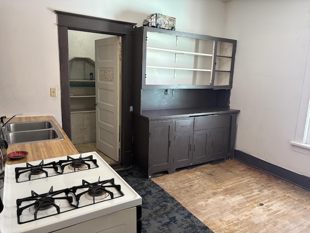 kitchen with white range with gas cooktop, gray cabinets, sink, and hardwood / wood-style floors