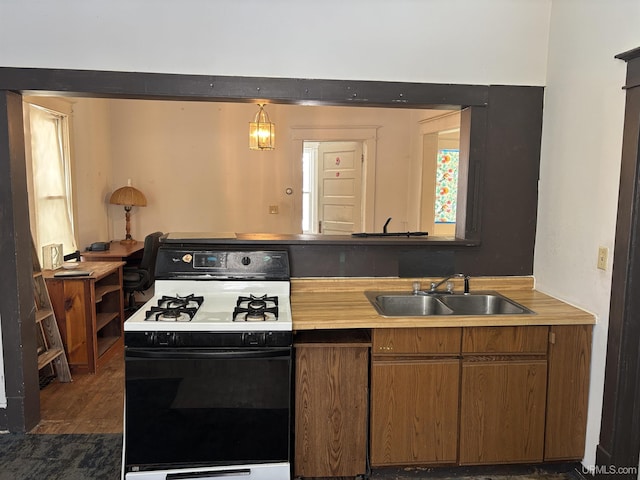 kitchen featuring dark hardwood / wood-style flooring, range with gas stovetop, sink, and hanging light fixtures