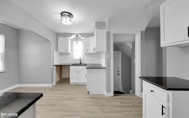 kitchen with white cabinetry, sink, tasteful backsplash, and light wood-type flooring