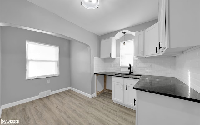 kitchen featuring white cabinetry, a healthy amount of sunlight, sink, and light wood-type flooring