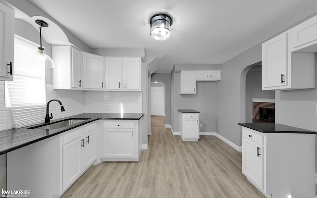 kitchen with backsplash, sink, hanging light fixtures, and white cabinets