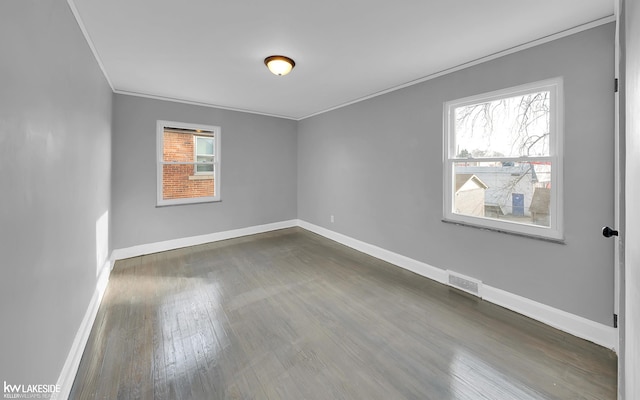 spare room featuring crown molding, plenty of natural light, and dark hardwood / wood-style floors