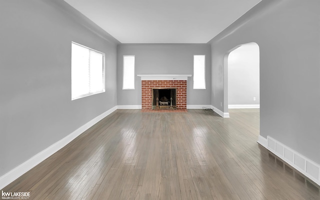 unfurnished living room with hardwood / wood-style floors and a brick fireplace