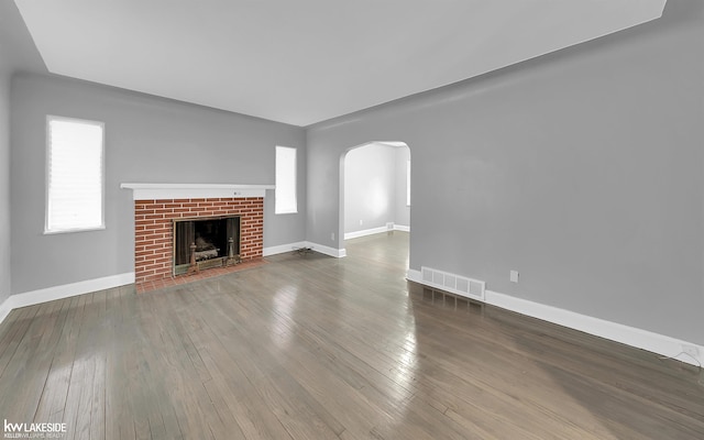 unfurnished living room with a brick fireplace and wood-type flooring