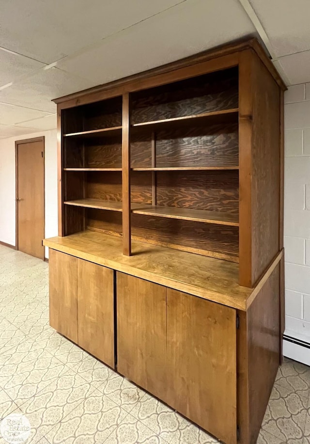 interior space featuring baseboard heating and a drop ceiling