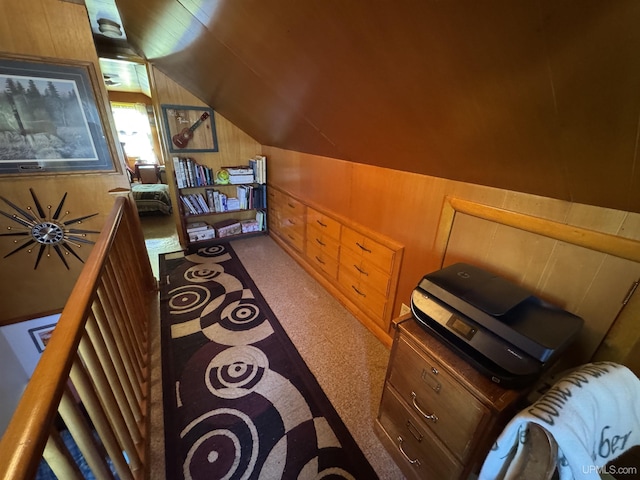 interior space featuring lofted ceiling, carpet floors, and wooden walls