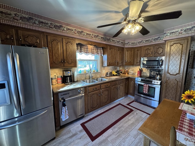 kitchen with sink, ceiling fan, stainless steel appliances, light hardwood / wood-style floors, and decorative backsplash