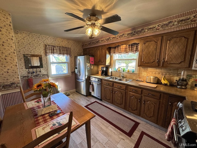 kitchen with stainless steel appliances, a healthy amount of sunlight, sink, and light hardwood / wood-style floors