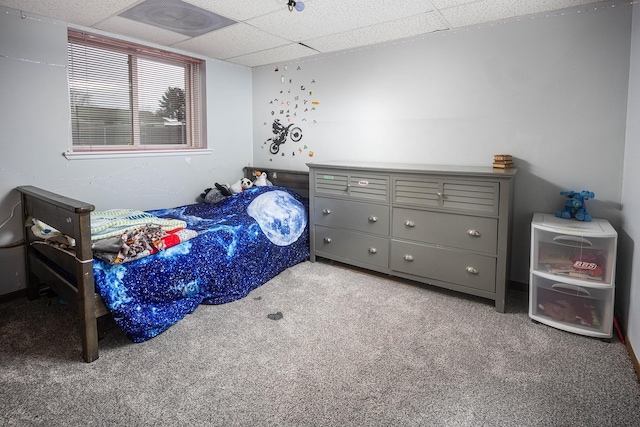 bedroom featuring a drop ceiling and light colored carpet