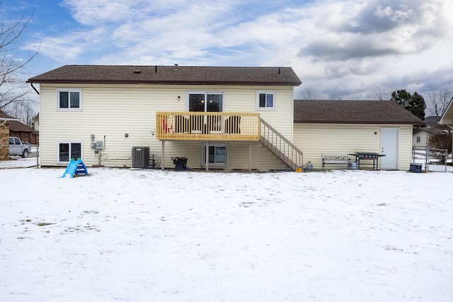 snow covered house featuring central AC unit and a deck