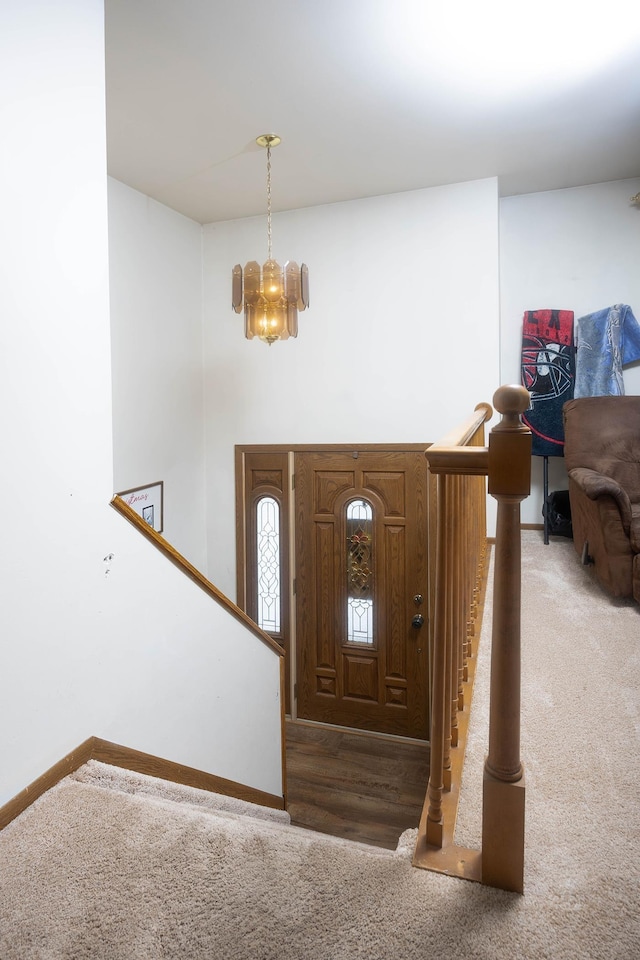 carpeted entryway featuring a notable chandelier