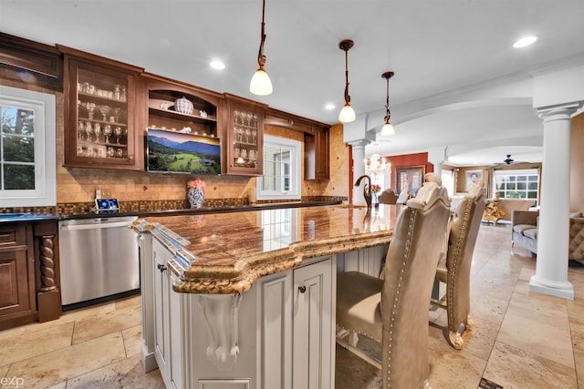 kitchen with dark stone countertops, decorative columns, tasteful backsplash, a kitchen bar, and stainless steel dishwasher