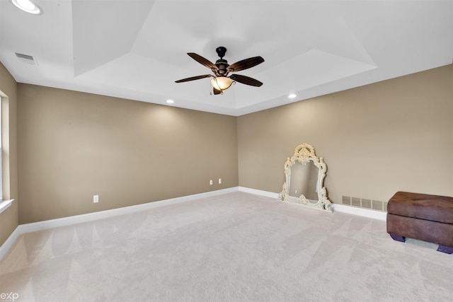 carpeted spare room featuring a raised ceiling and ceiling fan