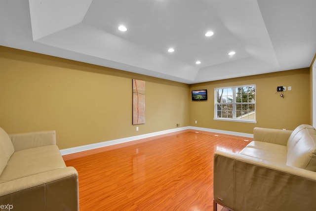 living room with wood-type flooring and a raised ceiling