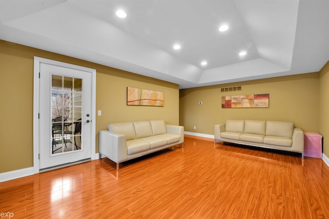 living room featuring light hardwood / wood-style floors and a raised ceiling