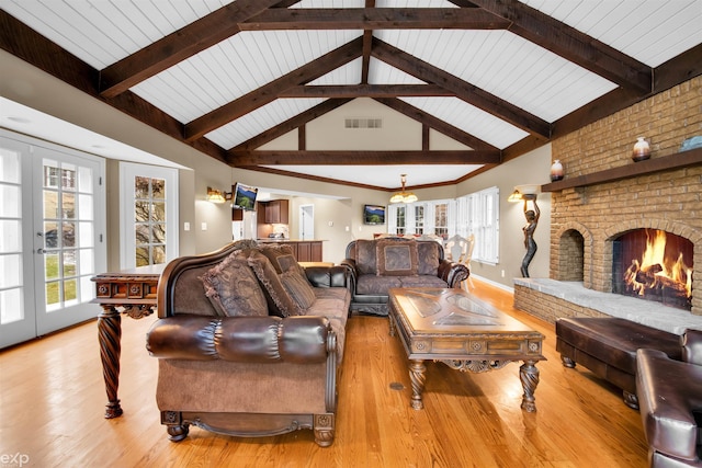 living room with a fireplace, beamed ceiling, and light wood-type flooring