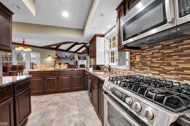 kitchen with decorative light fixtures, sink, backsplash, dark brown cabinetry, and stainless steel appliances