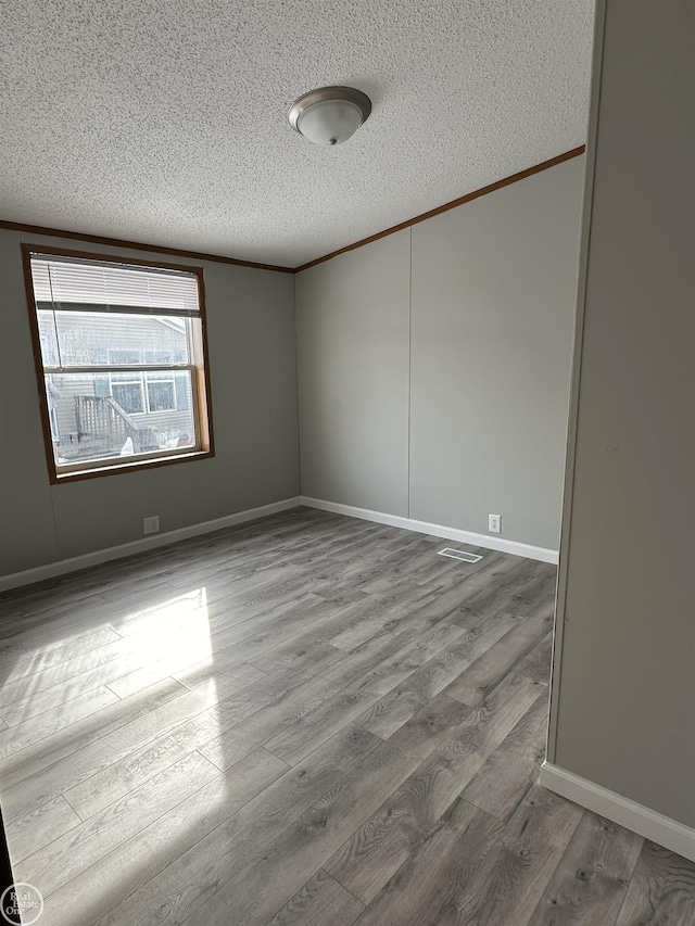 empty room with crown molding, hardwood / wood-style floors, and a textured ceiling