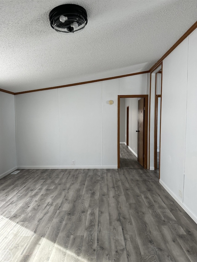 spare room with dark hardwood / wood-style flooring, crown molding, and a textured ceiling