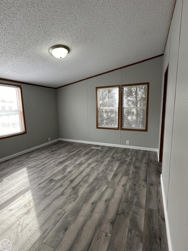 empty room with ornamental molding, wood-type flooring, and a textured ceiling