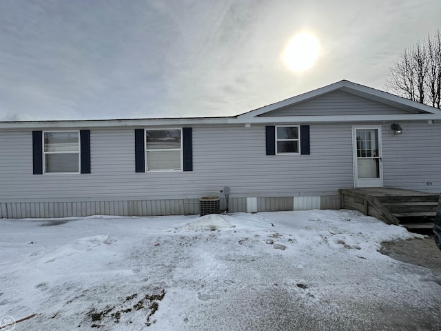 snow covered house featuring central AC unit